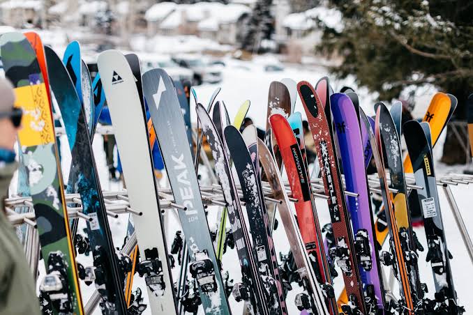Row of colorful skis standing upright in a snow-covered ski rack.