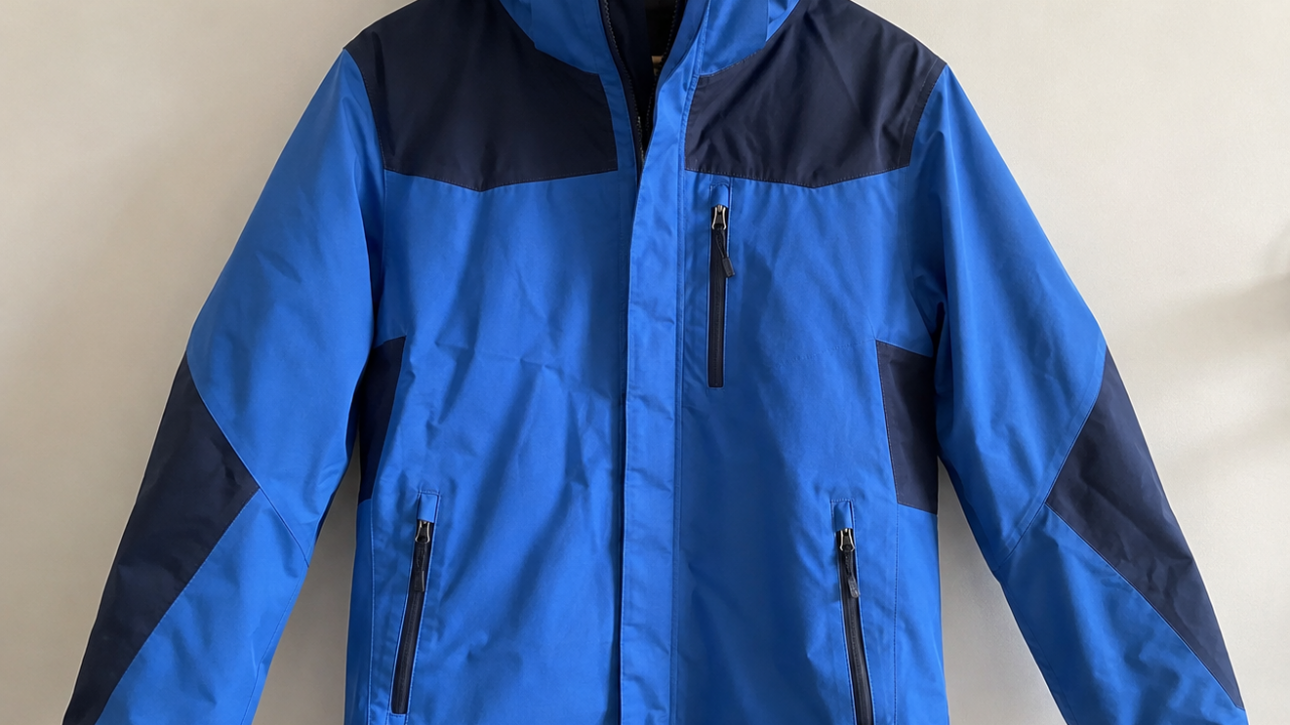 Blue and navy color-blocked winter jacket with hood on a wooden hanger (front view).